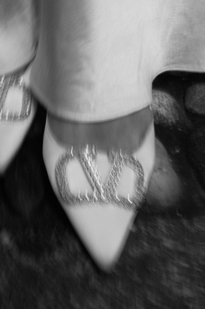 a bridal shoes of valentino on a cobblestone street, blurry black and white